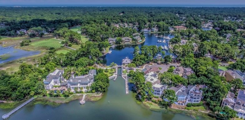 an aerial view of a community surrounded by lake and green trees