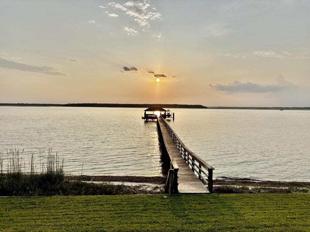a long wooden dock accross the beach during sunset